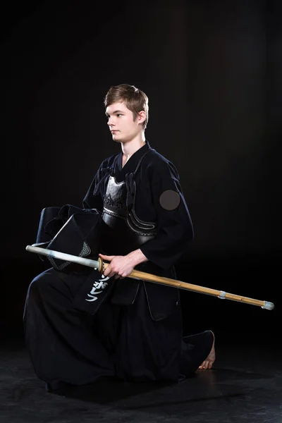 Young man practicing kendo with sowrd on black — Stock Photo