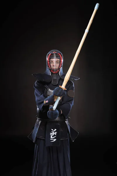 Combattant Kendo en armure pratiquant avec épée de bambou sur noir — Photo de stock