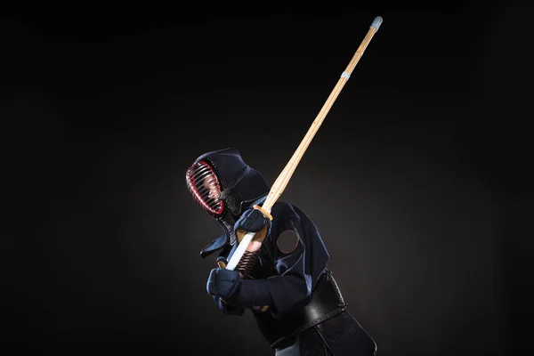 Combattant Kendo en armure pratiquant avec épée de bambou sur noir — Photo de stock