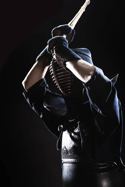 Kendo fighter in armor practicing with bamboo sword on black — Stock Photo