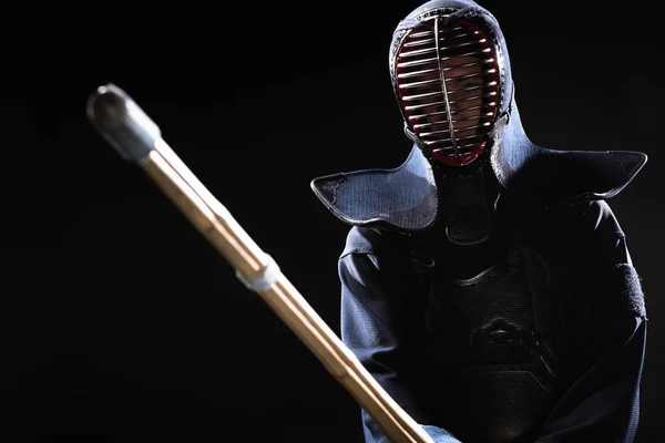 Kendo fighter in armor practicing with bamboo sword isolated on black — Stock Photo