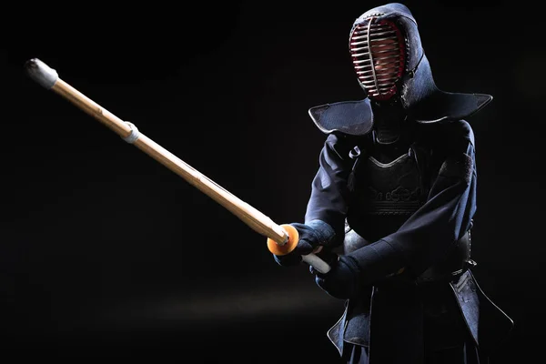 Боец Кендо в доспехах, практикующийся с бамбуковым мечом на черном — стоковое фото