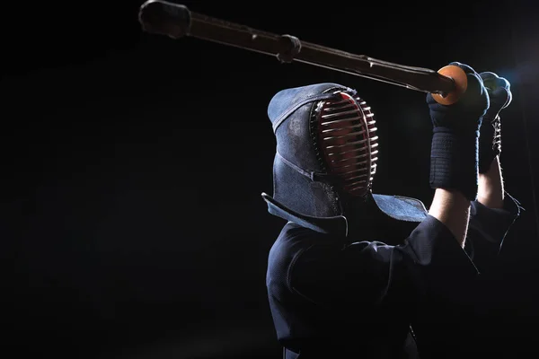 Kendo fighter in armor practicing with bamboo sword on black — Stock Photo