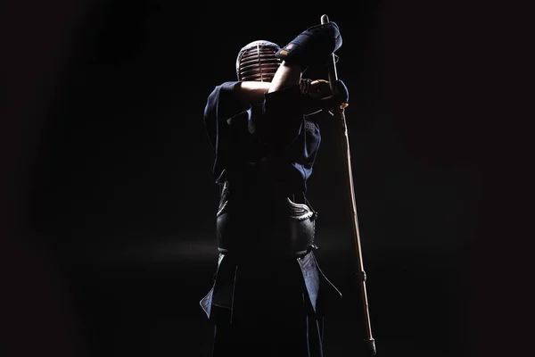 Combatiente Kendo en armadura practicando con espada de bambú sobre negro — Stock Photo