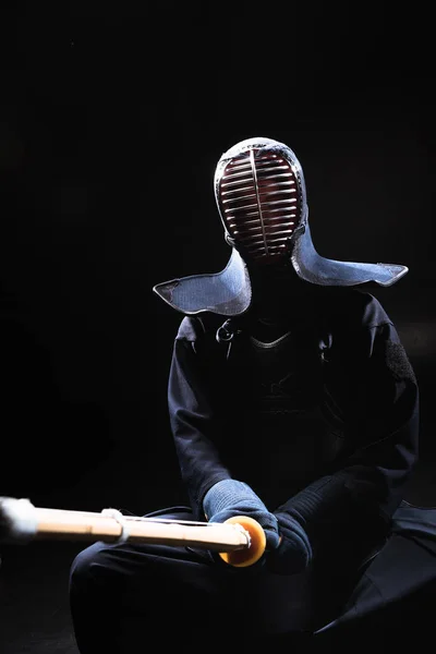 Kendo-Kämpfer im Helm mit Bambusschwert auf schwarz — Stockfoto