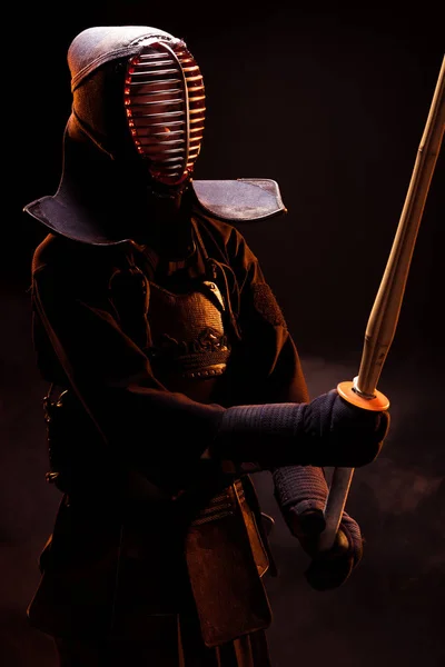 Kendo fighter in armor practicing with bamboo sword on black — Stock Photo