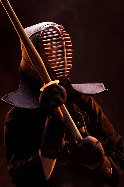 Kendo fighter in armor holding with bamboo sword on black — Stock Photo