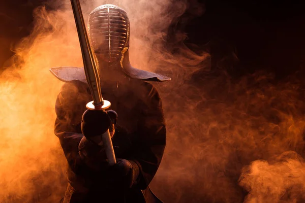 Combatiente Kendo en armadura sosteniendo espada de bambú en humo - foto de stock
