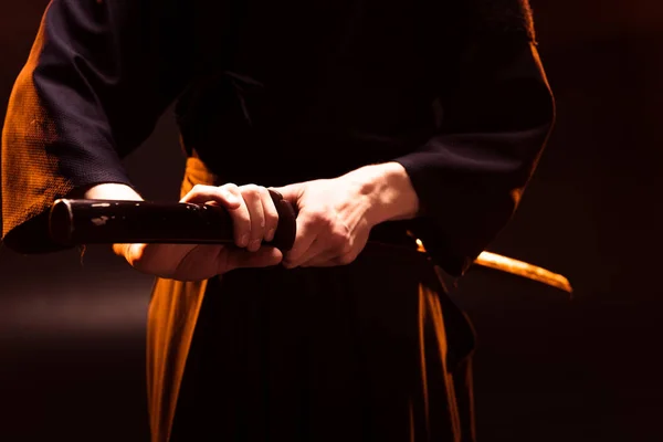 Partial view of kendo fighter holding bambo sword on black — Stock Photo