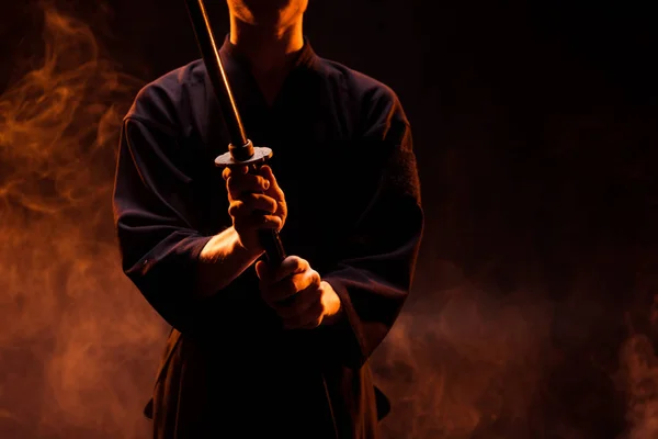 Cropped view of young man in kimono holding kendo sword in smoke — Stock Photo