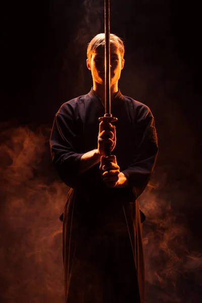 Молодий чоловік в кімоно тримає кендо меч в диму — стокове фото