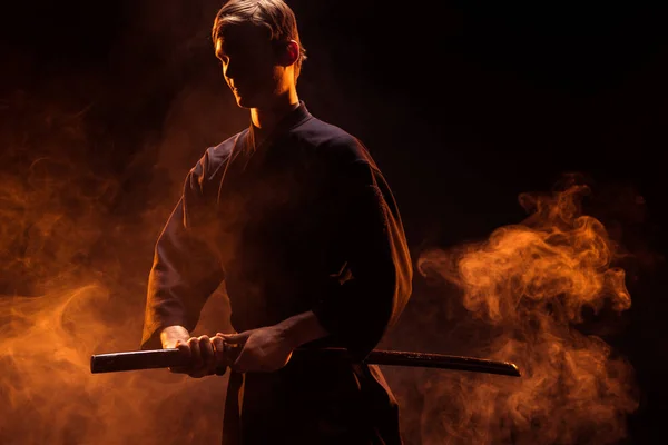 Young man in kimono holding kendo sword in smoke — Stock Photo