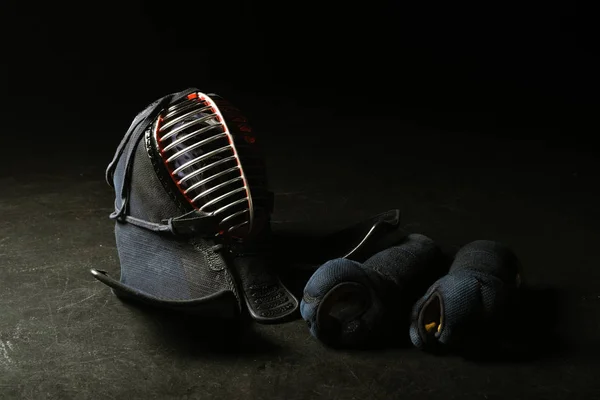 Kendo gloves and traditional helmet on dark surface — Stock Photo