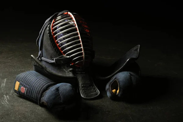 Kendo gloves and traditional helmet on dark surface — Stock Photo