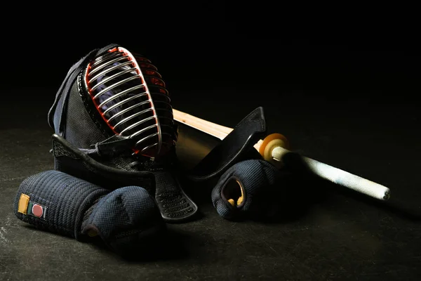 Кендо перчатки, шлем и бамбуковый меч на темной поверхности — стоковое фото