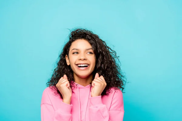 Encaracolado menina afro-americana sorrindo enquanto gesticulando isolado em azul — Fotografia de Stock