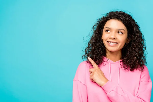 Happy curly african american woman pointing with finger isolated on blue — Stock Photo