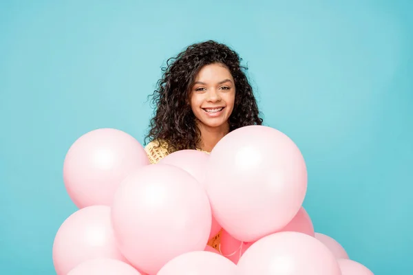 Feliz encaracolado menina americana africana perto de balões de ar rosa isolado em azul — Fotografia de Stock