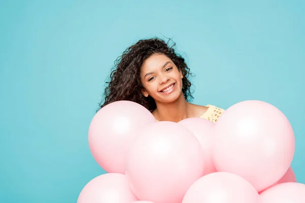 Feliz rizado africano americano chica cerca rosa aire globos aislado en azul — Stock Photo