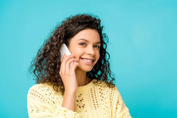 Красивая африканская американка улыбается, разговаривая на смартфоне, изолированном на голубом — стоковое фото