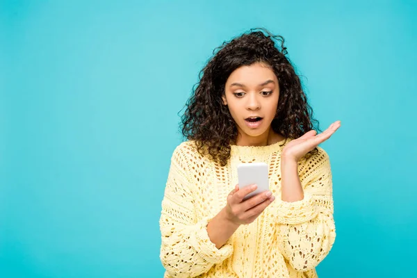 Sorprendió a la mujer afroamericana mirando el teléfono inteligente aislado en azul - foto de stock