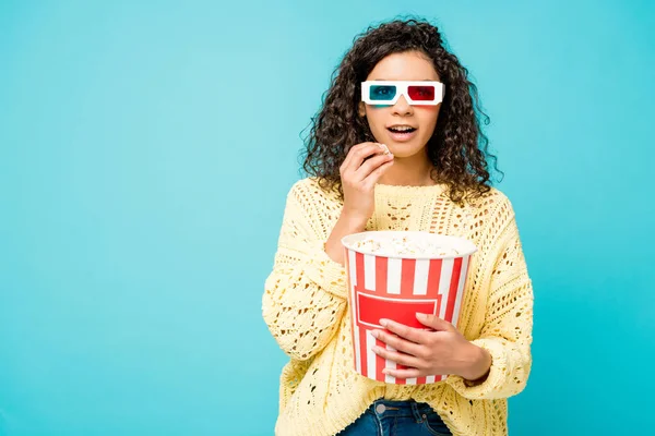 Surprised curly african american woman  in 3d glasses eating popcorn isolated on blue — Stock Photo
