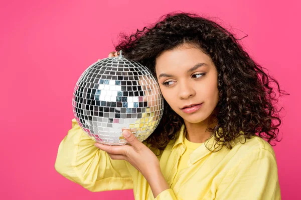 Schöne lockige afrikanisch-amerikanische Frau hält glänzende Discokugel isoliert auf purpurrot — Stockfoto