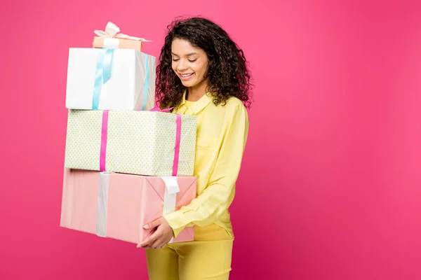 Fröhliche lockige afrikanisch-amerikanische Frau hält Geschenkboxen isoliert auf Purpur — Stockfoto