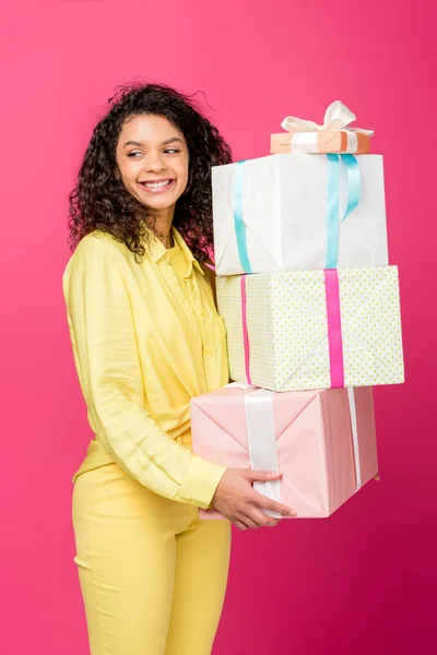 Feliz rizado africano americano mujer celebración regalo cajas aislado en carmesí - foto de stock