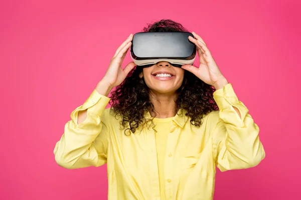 Happy african american woman wearing virtual reality headset isolated on crimson — Stock Photo