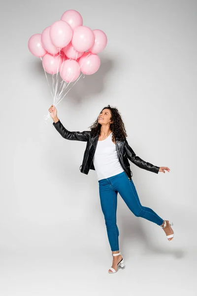 Fröhliche afrikanisch-amerikanische junge Frau mit rosa Luftballons auf grau — Stockfoto
