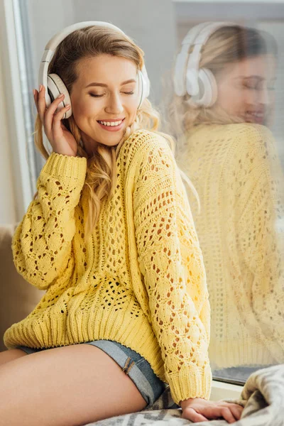 Bella sorridente giovane donna in cuffia ascoltare musica a casa — Foto stock