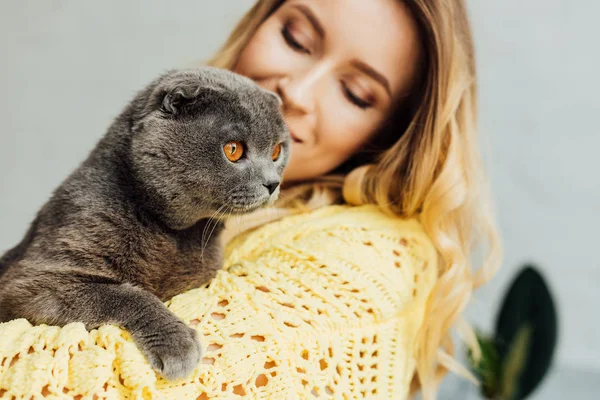 Hermosa chica en punto suéter celebración escocés plegable gato - foto de stock