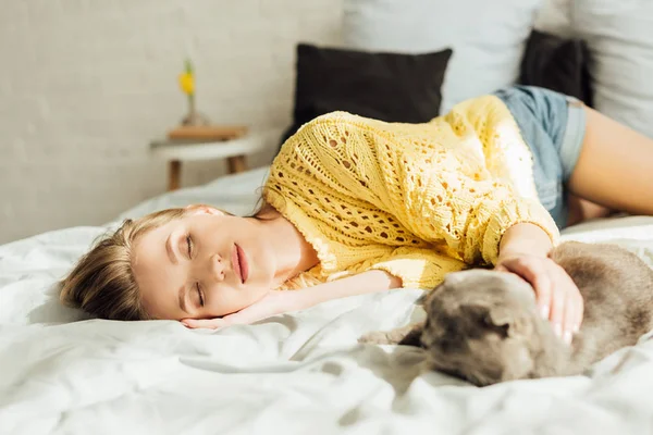 Foyer sélectif de belle jeune femme dormant au lit avec chat pliant écossais — Photo de stock