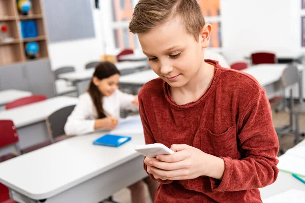 Studente interessato in piedi in classe e utilizzando smartphone durante il freno — Foto stock