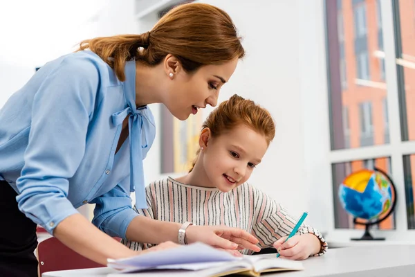 Enseignant en chemisier bleu expliquant la leçon à l'élève en classe — Photo de stock