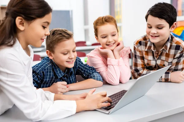 Happy preteen pupils using laptop in classroom with smile — Stock Photo