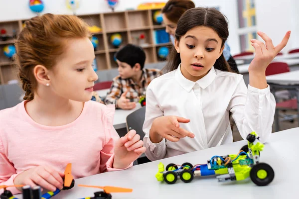 Elèves assis au bureau avec des jouets éducatifs pendant les cours en classe — Photo de stock