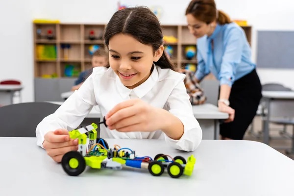 Smiling schoolgirl playing with educational toy during lesson in class — Stock Photo