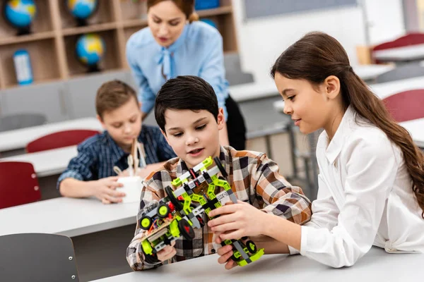 Alumnos sentados en el escritorio con juguetes durante la clase en el aula - foto de stock
