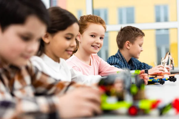 Alumnos sentados en el escritorio con juguetes durante la clase en el aula - foto de stock