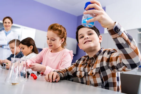 Curious pupils sitting at desk and studying chemistry in classroom — Stock Photo