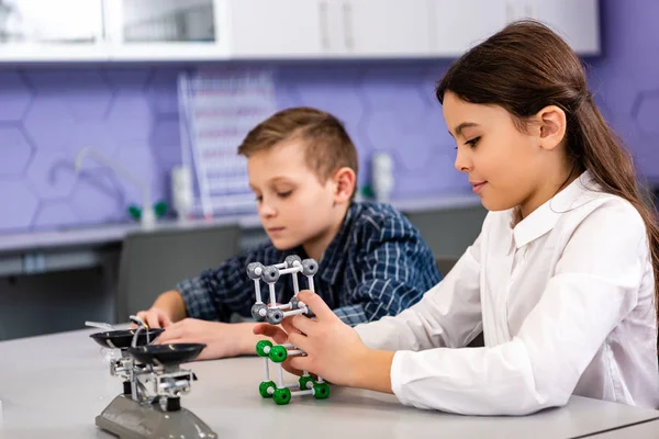 Pupils holding molecule structures while sitting in classroom during chemistry lesson — Stock Photo