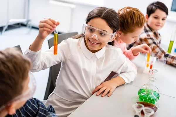 Alunos em óculos de proteção segurando frascos durante a aula de química — Fotografia de Stock