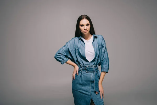 Belle et brune femme en denim robe avec la main sur la hanche en regardant la caméra — Photo de stock