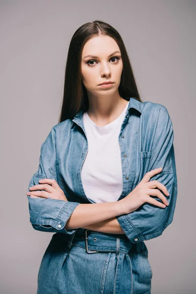 Young adult and beautiful woman in denim dress with crossed arms isolated on grey — Stock Photo