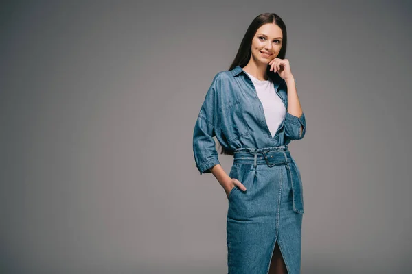 Donna sorridente e bella in denim vestito con mano in tasca guardando altrove — Foto stock