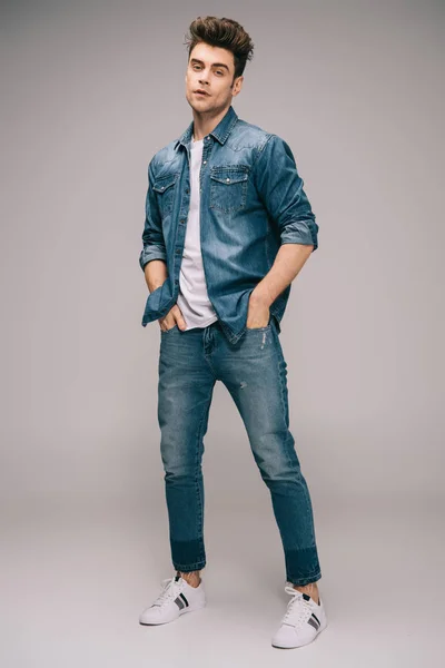 Bel homme en jeans, jupe et t-shirt avec les mains dans les poches regardant la caméra — Photo de stock