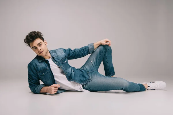 Handsome man in jeans, skirt and t-shirt lying on floor and looking at camera — Stock Photo