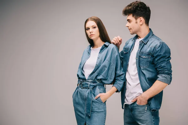 Freundin im Jeanskleid und Freund in Jeans und Hemd auf grauem Hintergrund — Stockfoto